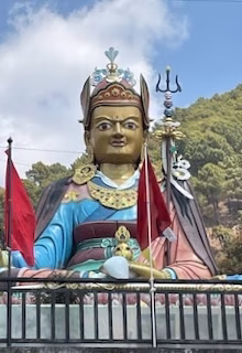 Colorful Indian idol statue with flags and trident, outdoor mountain setting, cultural festival decor.