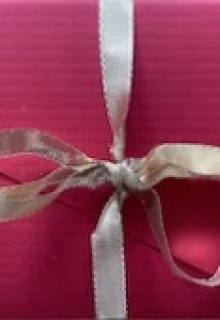 Elegant pink gift box with beige ribbon and bow, perfect for special occasions.